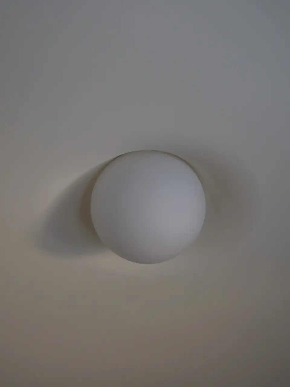 Close view of the PLST 37 opal glass globe, half sunk into a skimmed plaster ceiling