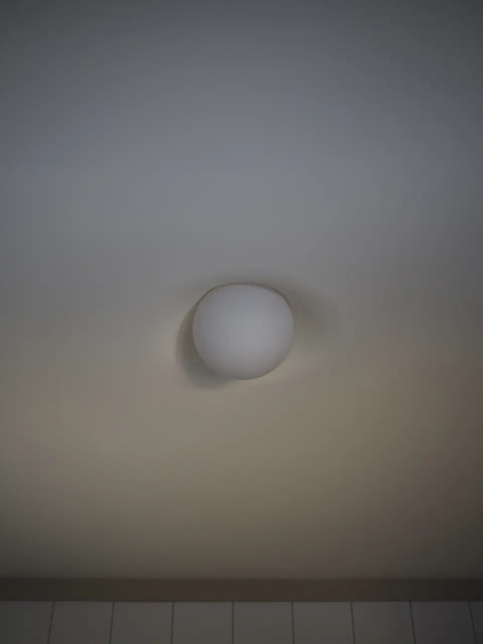 PLST 37 plaster mud-in light by Brendan Tadler on a soft grey ceiling, the globe casting a crescent of shadow