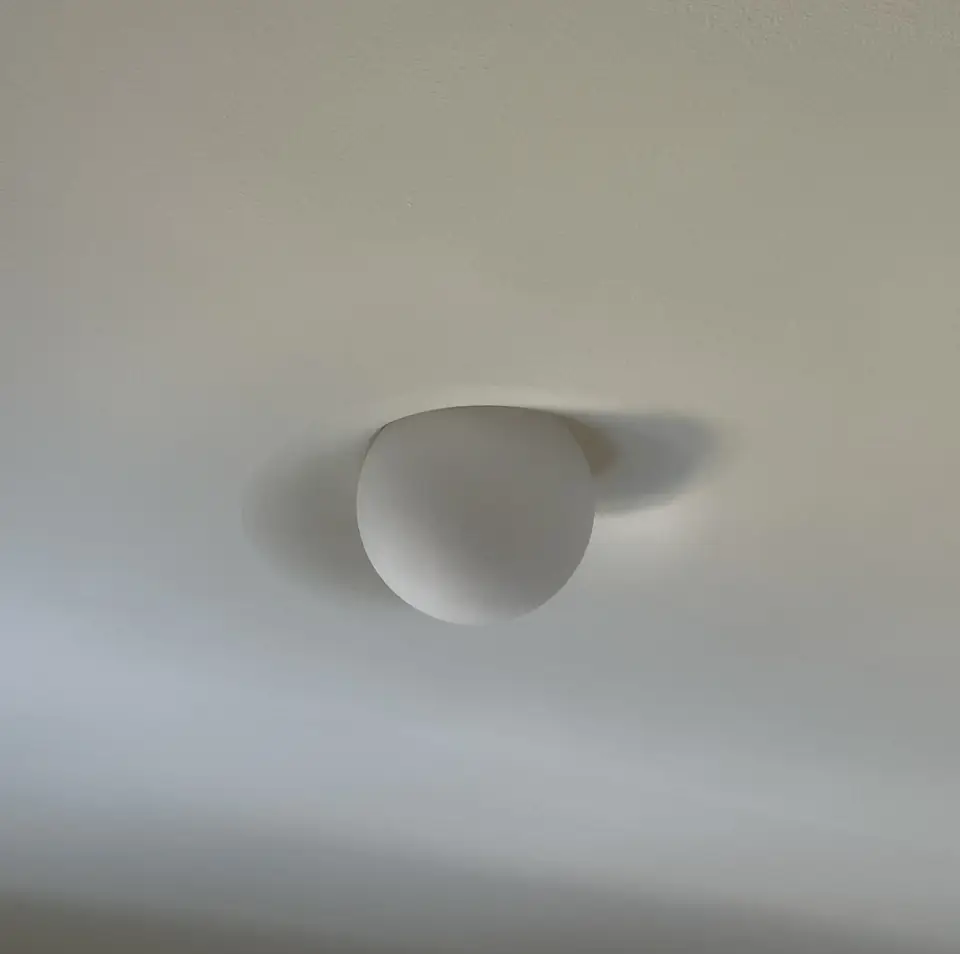 Low angle view of PLST 37, the globe and its shadow on a flush plaster ceiling
